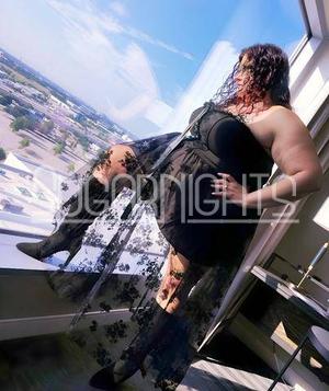 Ashley Bankston in Dallas posing by a window in a black lace dress and heels